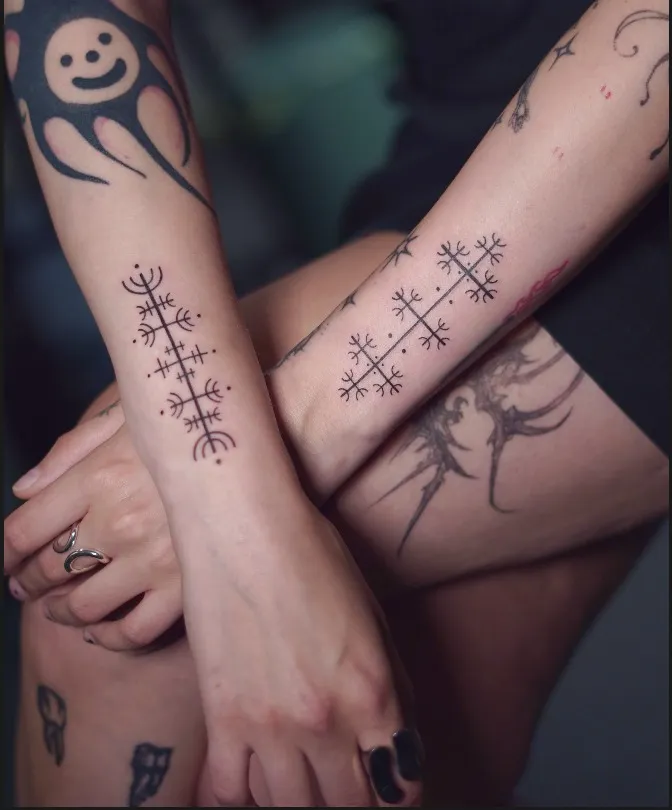 Fine line Nordic stave tattoos on the forearms featuring symmetrical protective symbols and delicate linework.